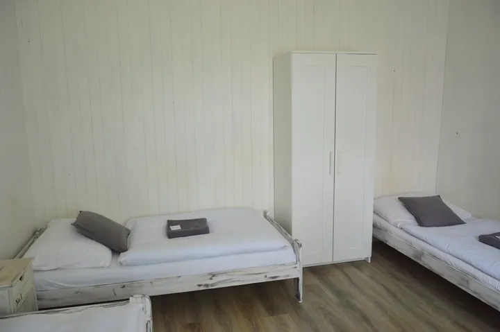 Světlý pokoj se dvěma lůžky a bílou skříní