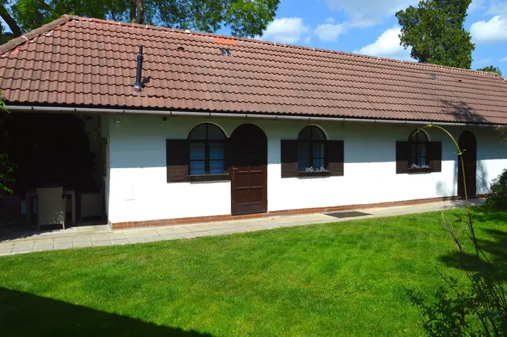 Bílá budova penzionu s červenou střechou a trávníkem